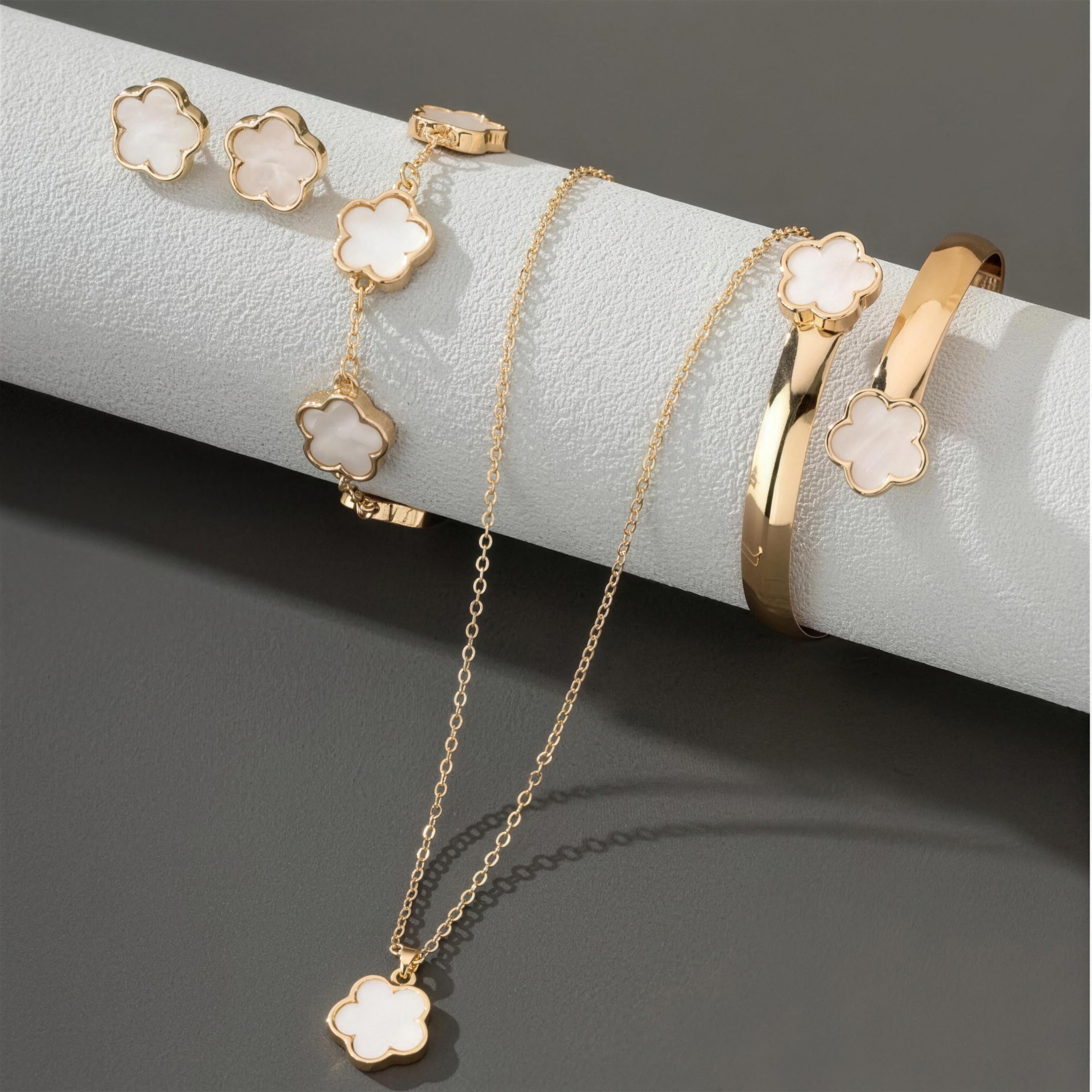 White clover jewelry set displayed, necklace, bracelet, bangle and earrings in gold